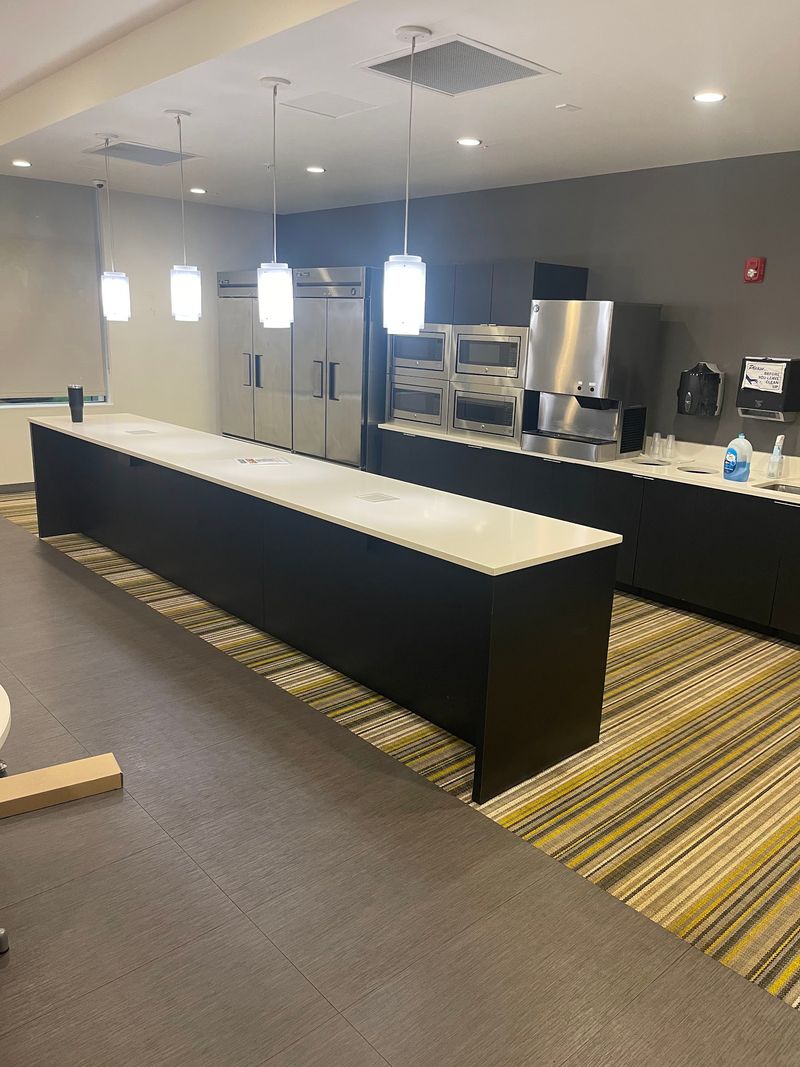 Commercial break room kitchen with striped yellow and gray carpet in the aisles