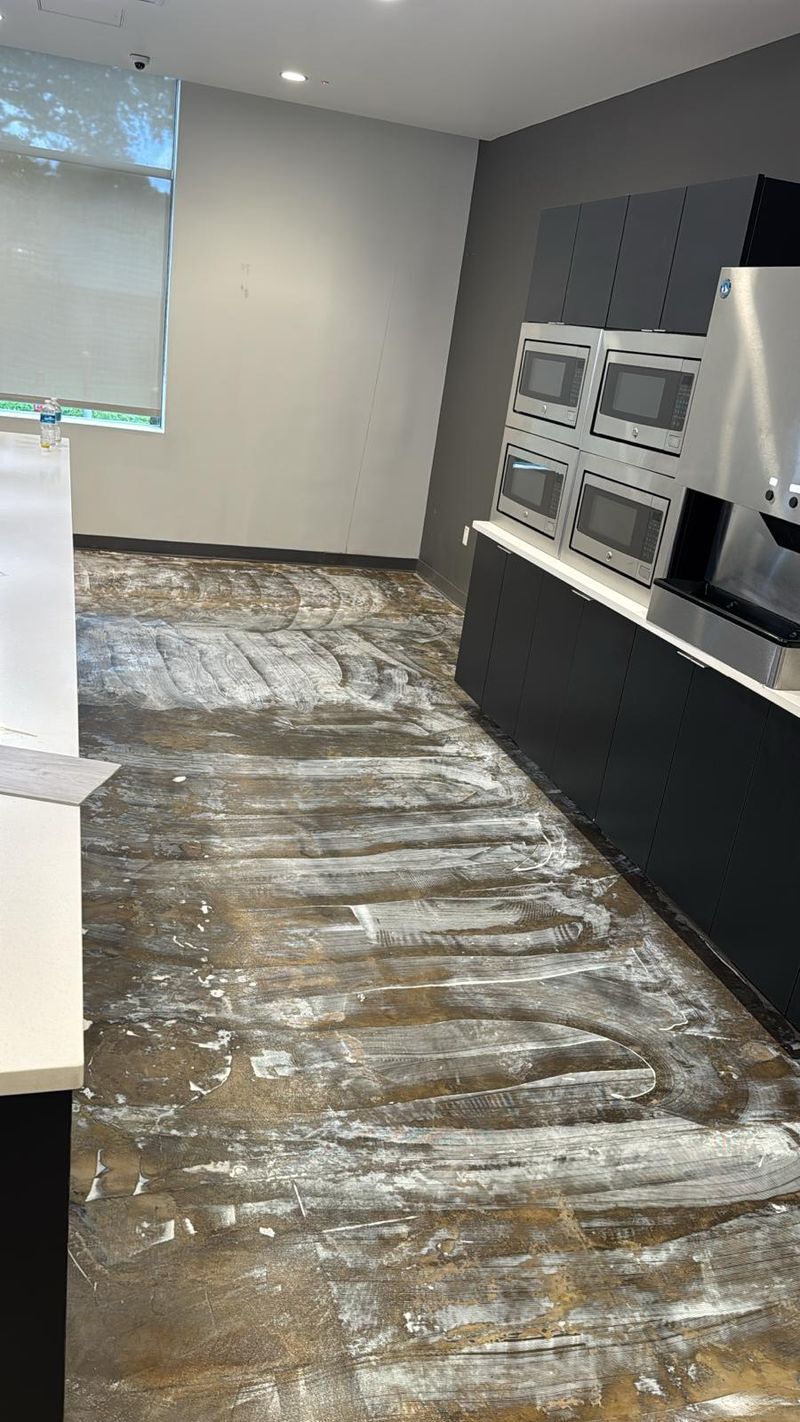 Kitchen aisle with carpet removed and old adhesive on the concrete slab