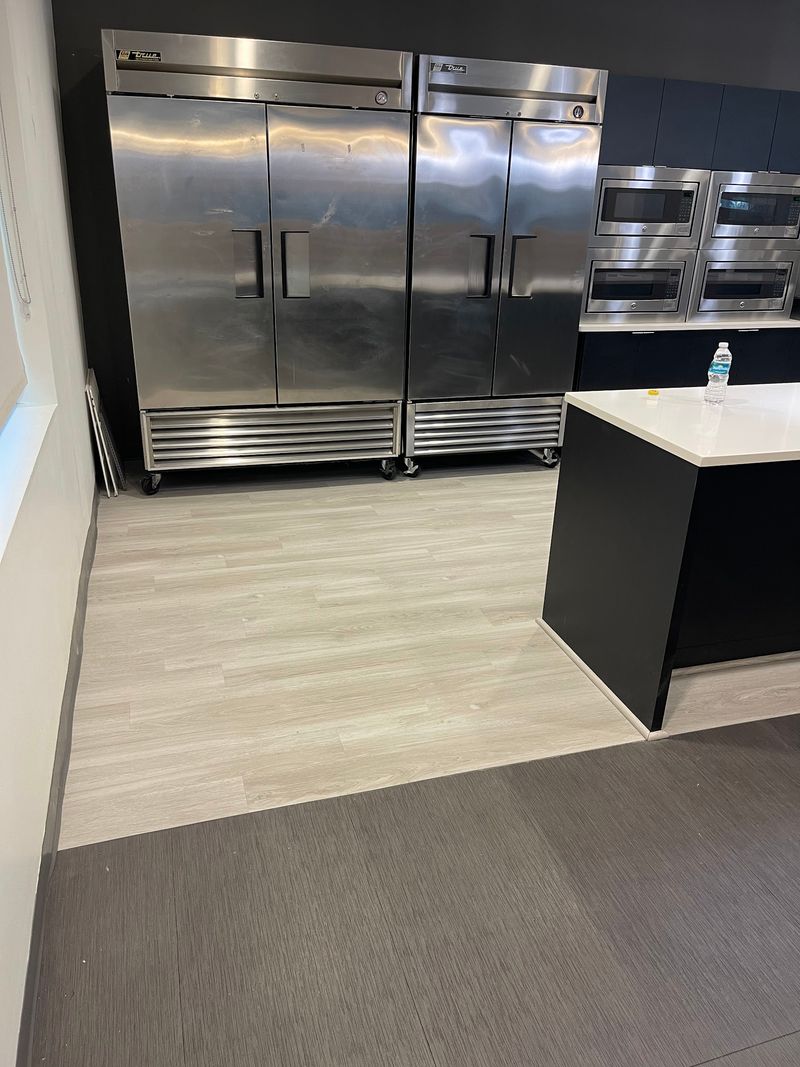 Light gray wood-look plank floor in front of stainless steel refrigerators