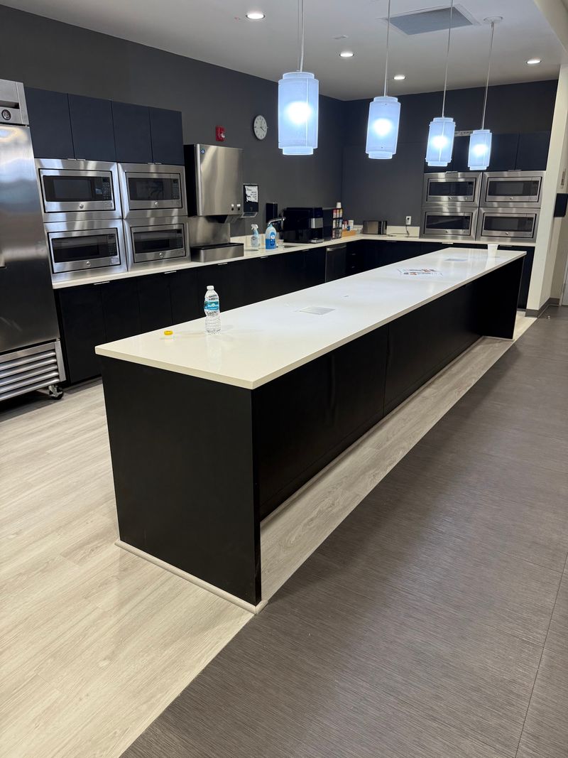 Commercial kitchen with long island and new light gray wood-look plank flooring