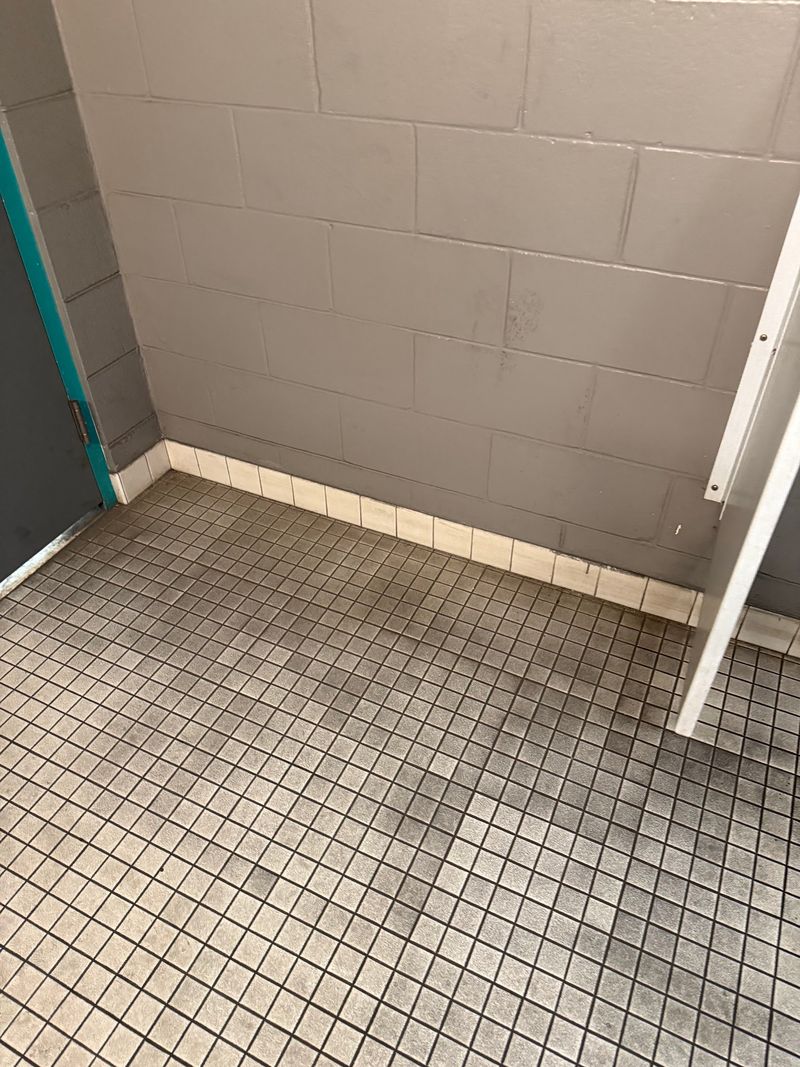 Close view of stained gray mosaic tile in a commercial restroom corner