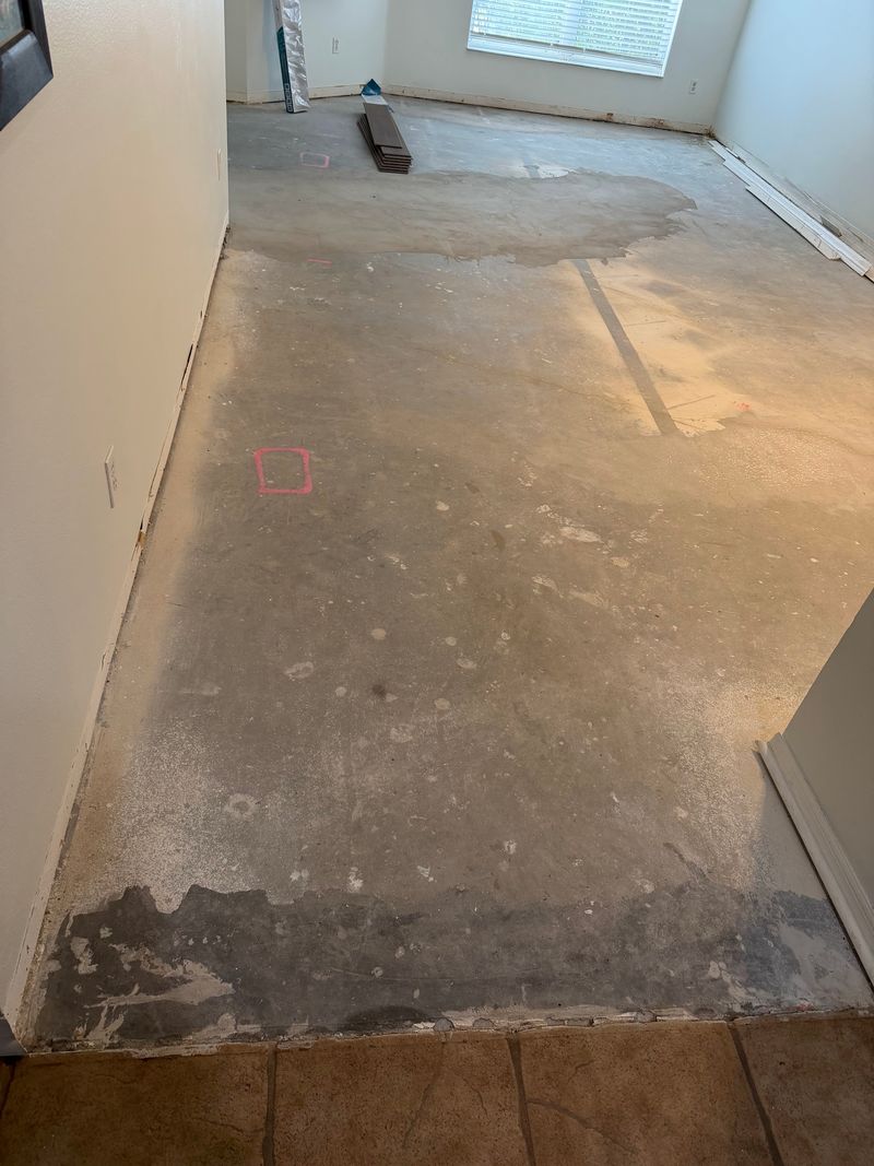 Bare concrete slab with leveling patches in a long living room