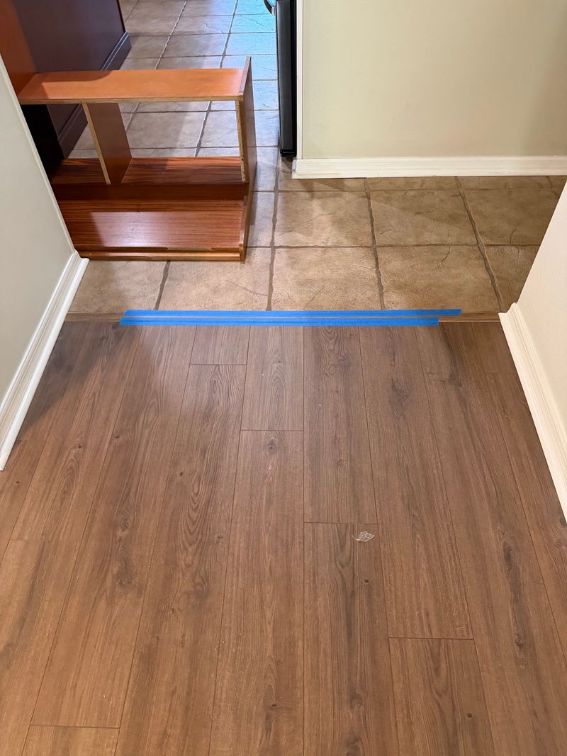 Dark brown wood-look planks meeting the existing tile at a doorway