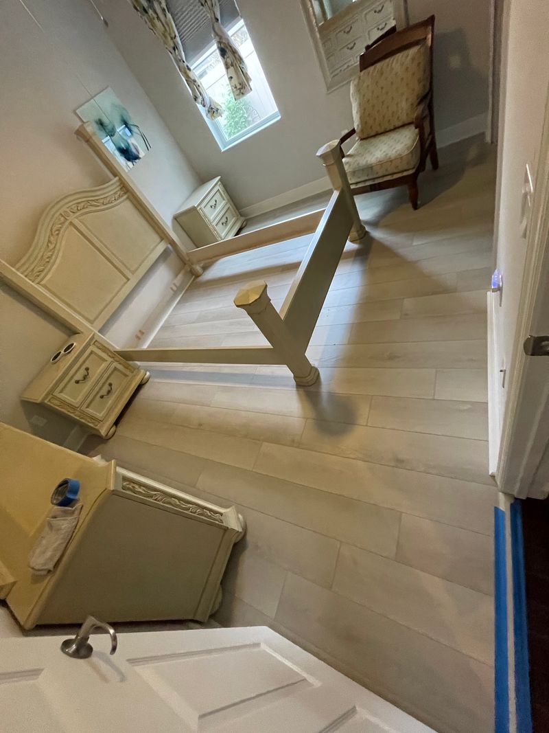 Bedroom with light whitewashed wood-look plank flooring and cream furniture