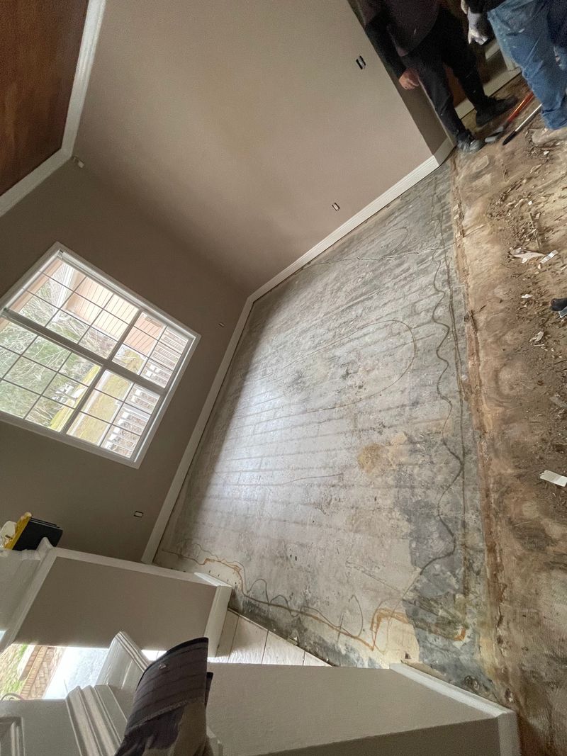 Old plank floor pulled up, exposing the concrete slab with adhesive lines