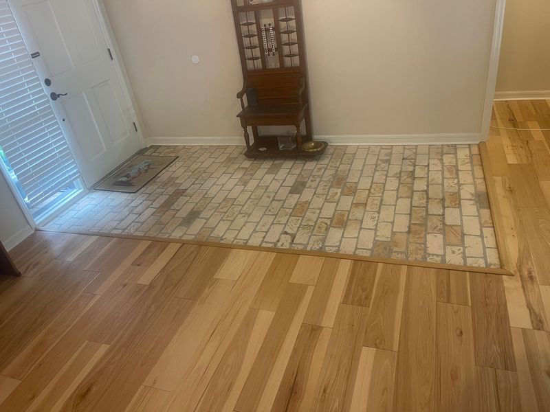 Entry with light natural hardwood flooring framing a brick paver landing