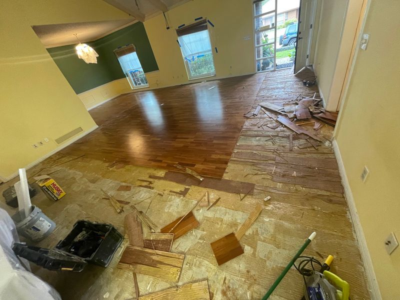 Living room with old glossy plank flooring partly torn out during removal