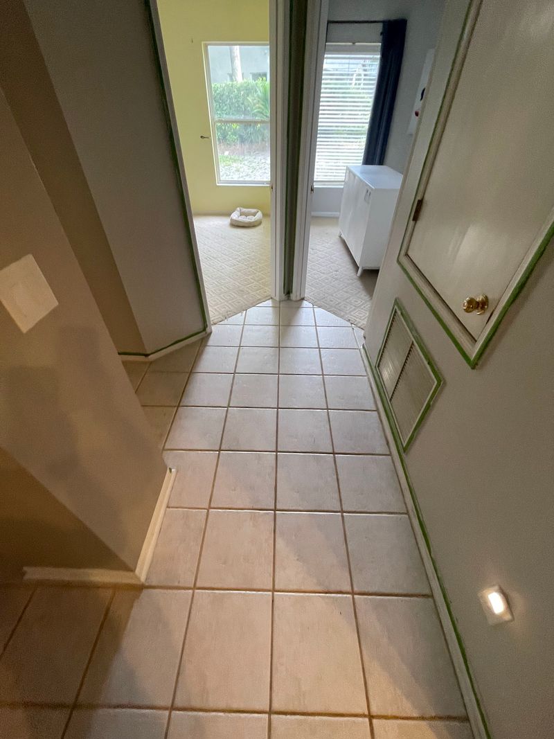 Hallway with beige ceramic tile running to a sunlit room