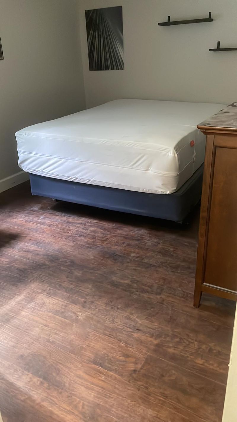 Bedroom with dark brown wood-look laminate flooring and white baseboards