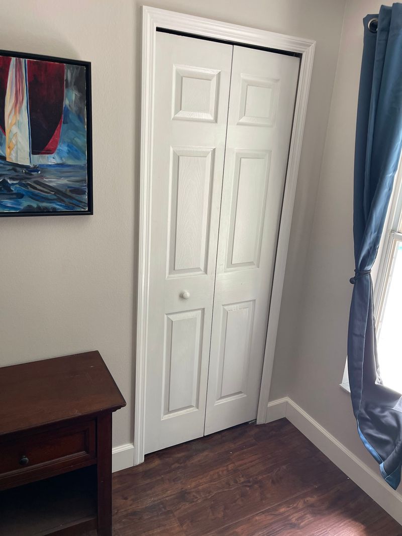 Closet doors and dark brown laminate flooring in a bedroom corner