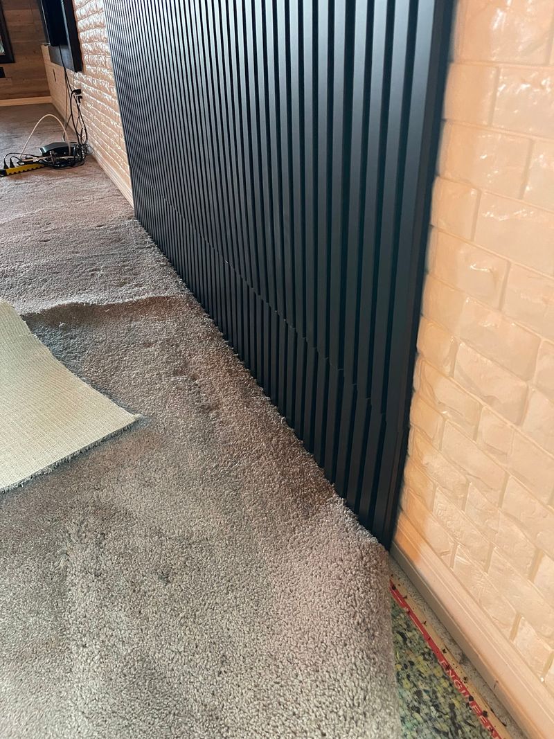 Carpet pulled back along a dark slatted accent wall