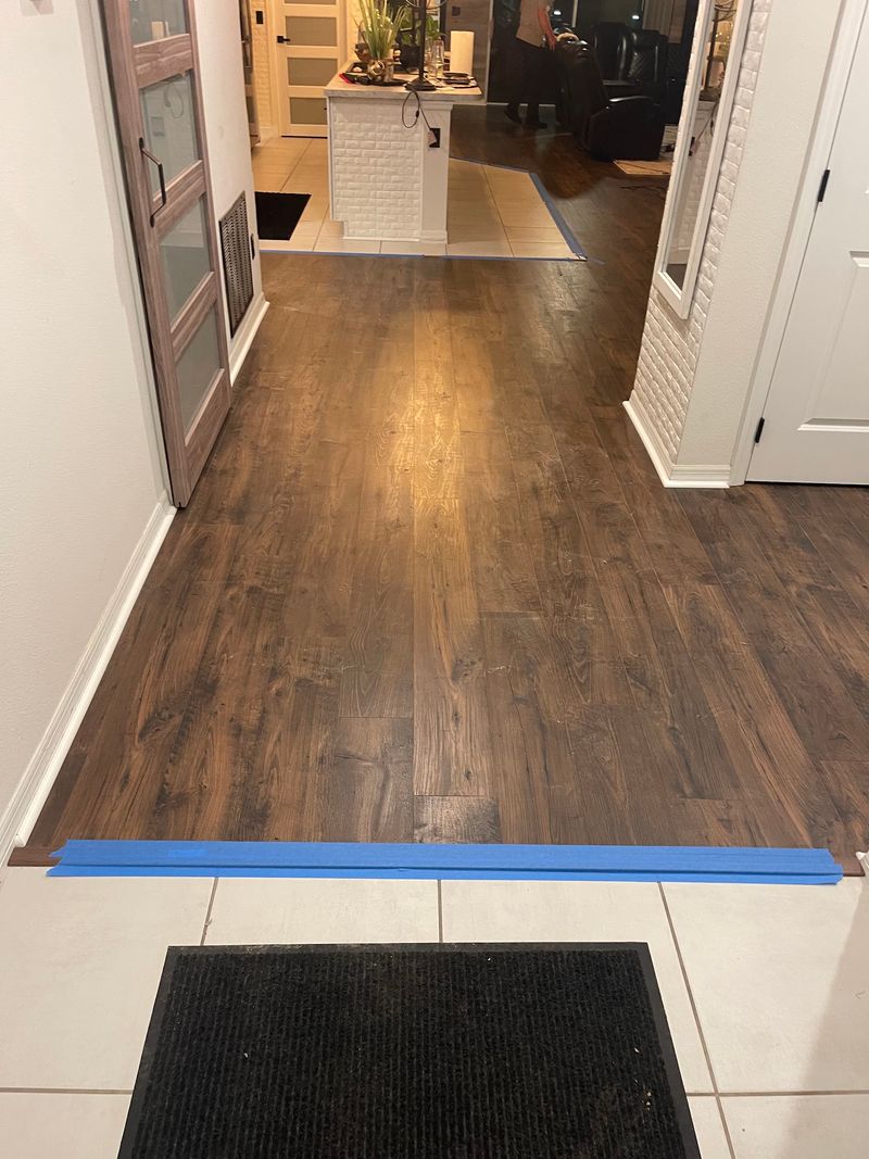 Hallway with new dark brown laminate flooring meeting the tile entry