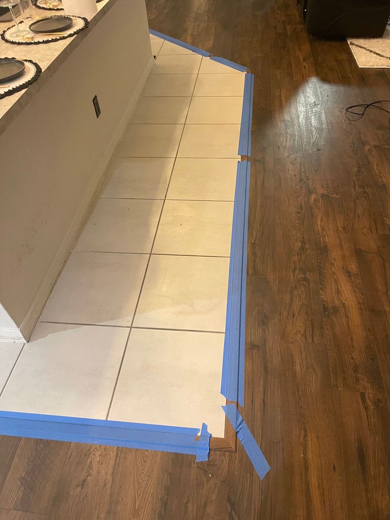 Dark brown laminate fitted along the tile kitchen floor edge