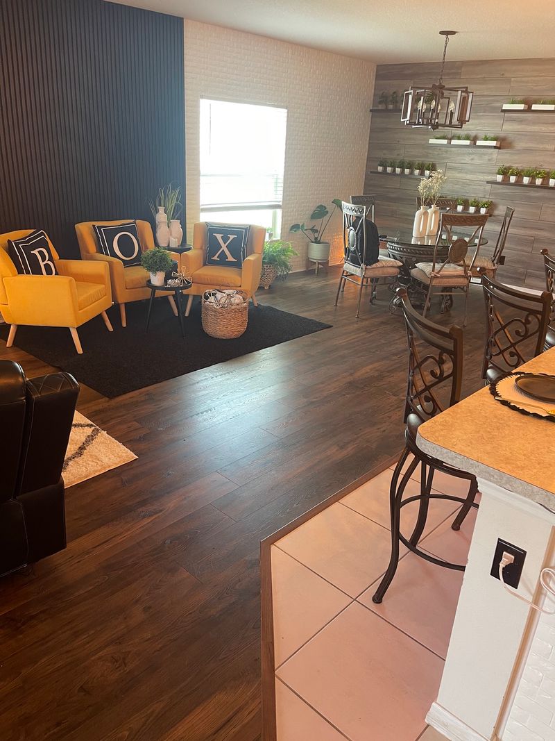 Open living and dining area with dark brown laminate flooring beside a tile kitchen