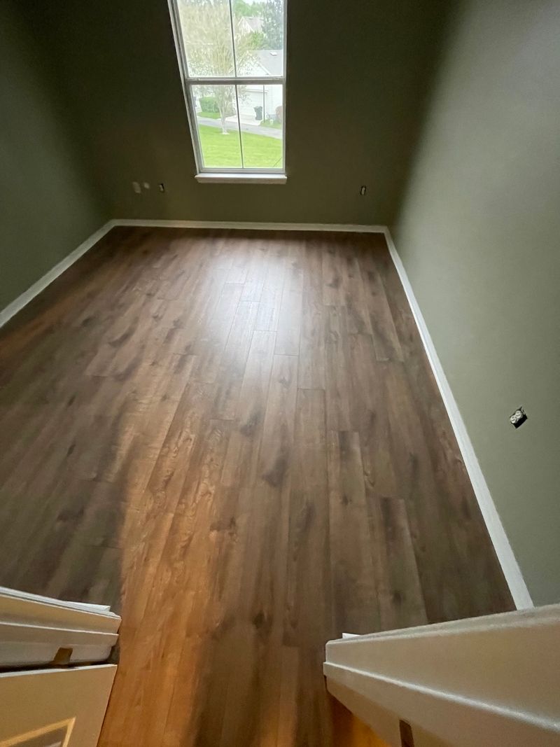 Bedroom with window and new brown laminate floor seen from the doorway