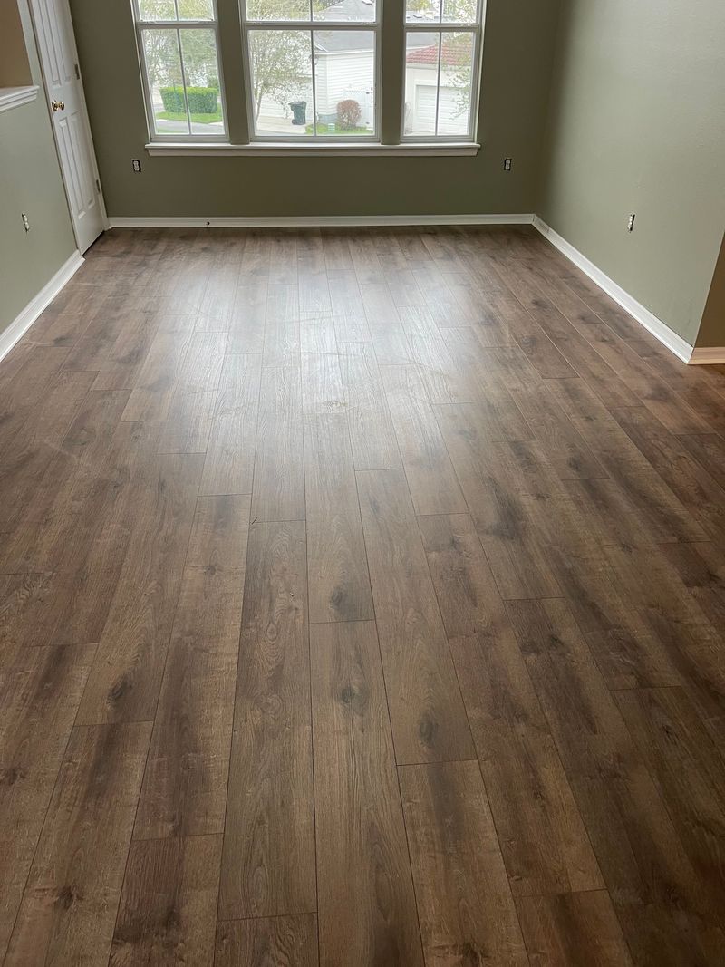 Bright bedroom with brown oak-look laminate flooring and white baseboards
