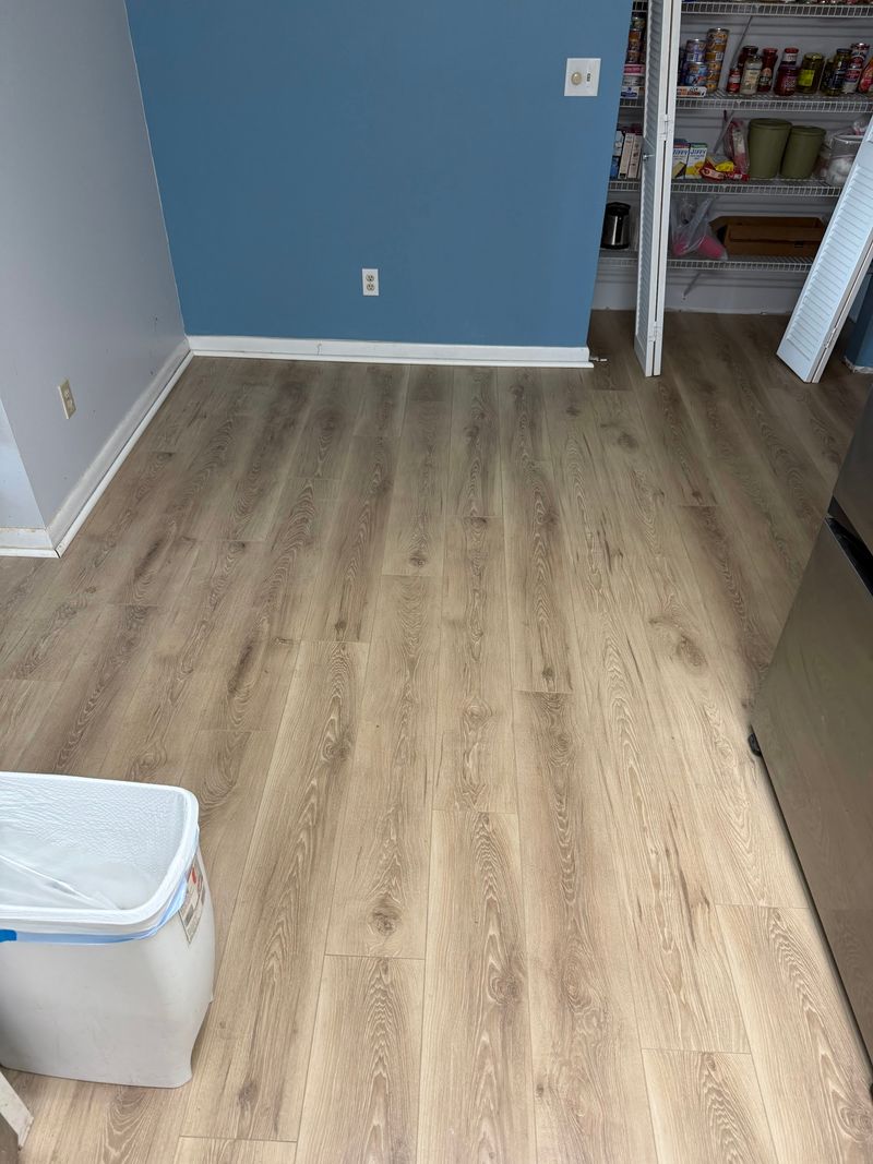 Room with blue walls and new light oak laminate flooring with white baseboards