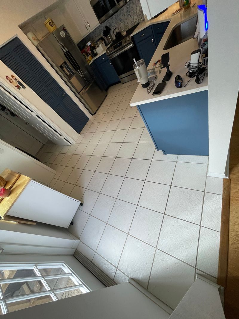 Kitchen with white tile floor and navy lower cabinets before the new floor
