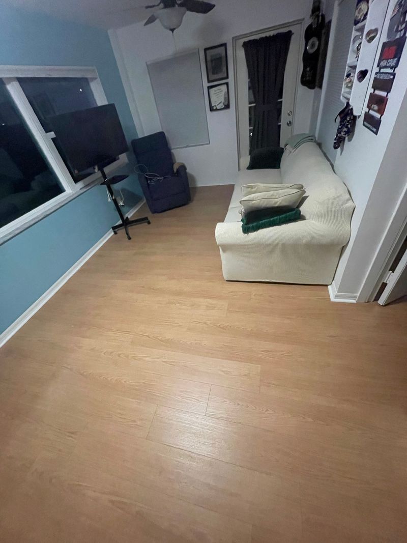 Living room with light oak-look laminate flooring, white sofa and blue walls