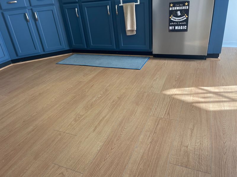 Light oak-look laminate flooring in front of navy kitchen cabinets