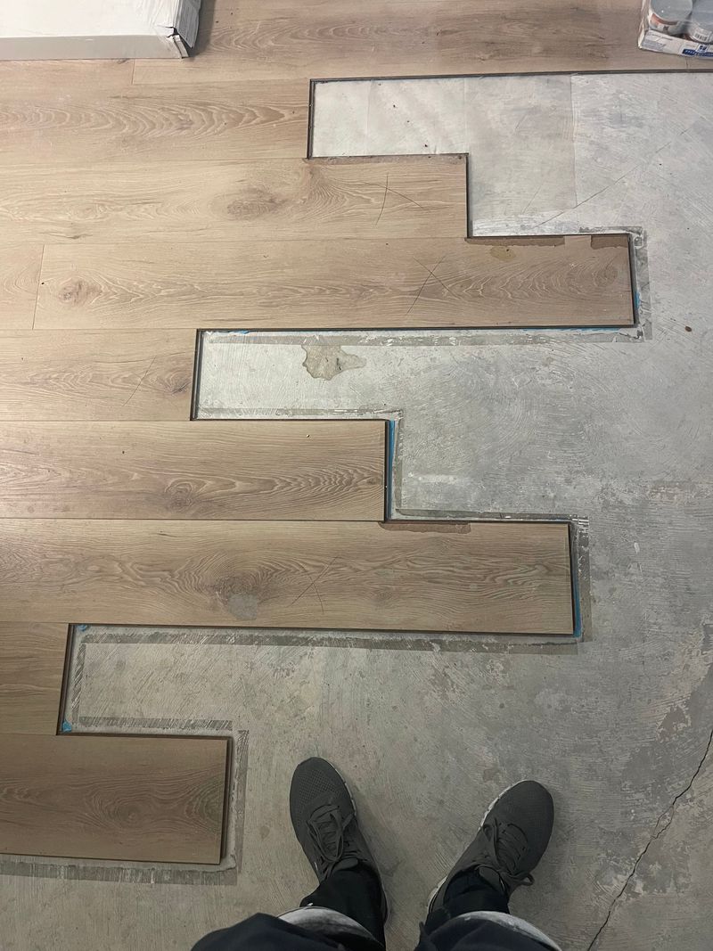 Light oak laminate planks being laid over a concrete slab