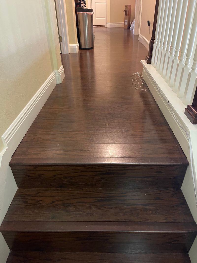 Upstairs hallway with dark espresso plank flooring at the top of the stairs