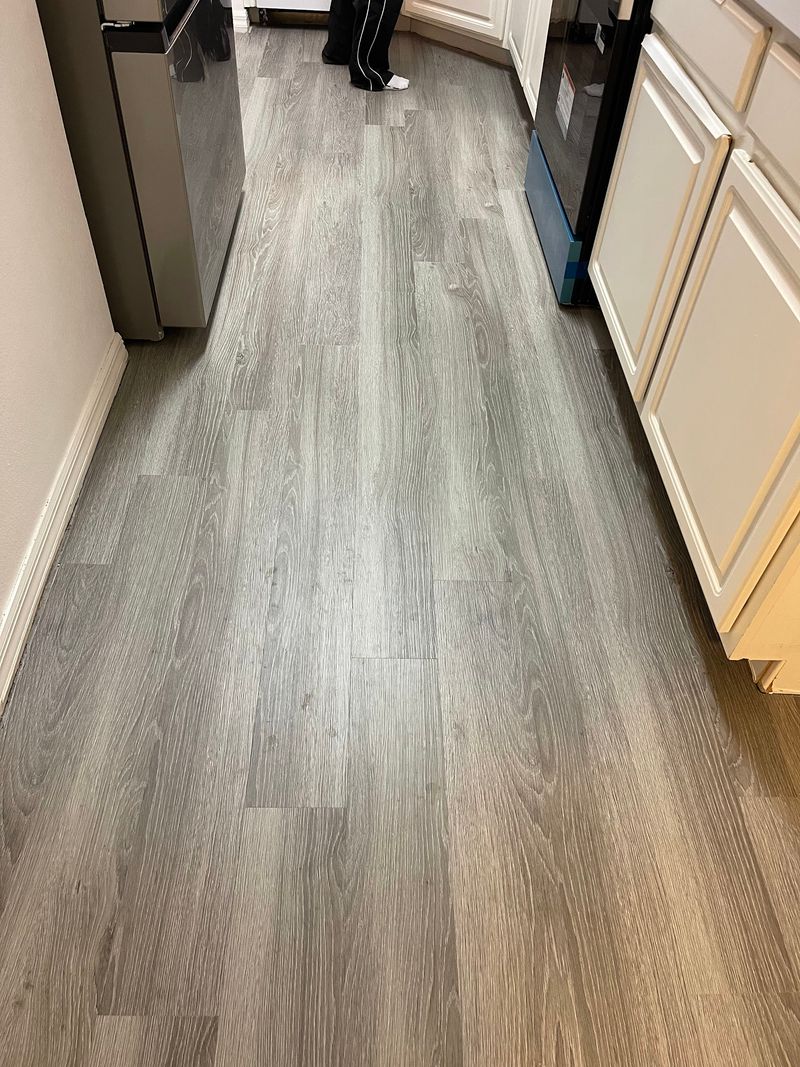 Galley kitchen with long gray wood-look vinyl planks and white cabinets