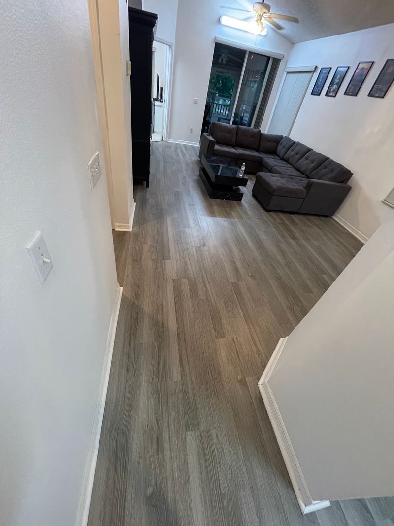 Hallway opening to the living room with new gray wood-look vinyl plank