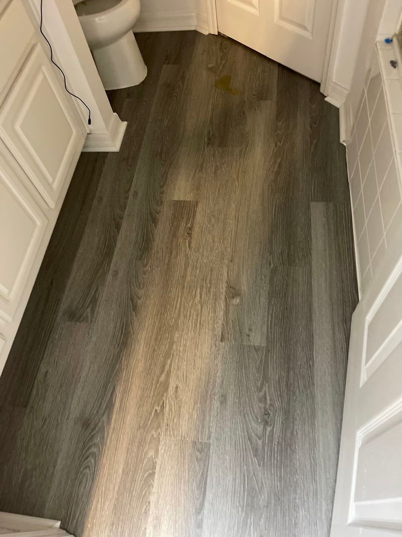 Bathroom with gray wood-look vinyl plank flooring and white vanity