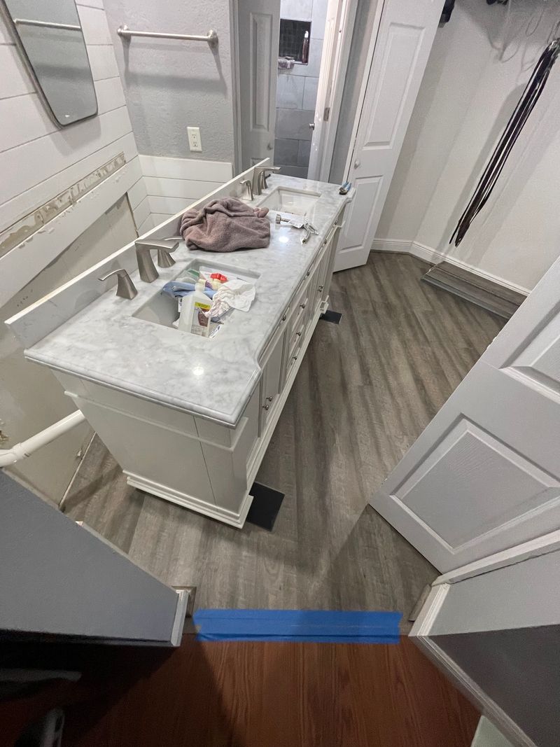 Bathroom with gray wood-look vinyl plank flooring in front of a double vanity