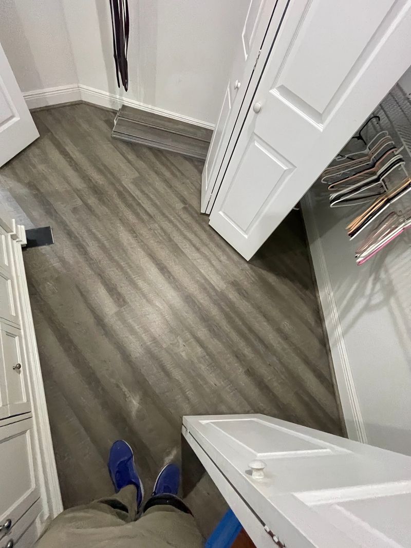 Walk-in closet with gray wood-look vinyl plank flooring and white shelving