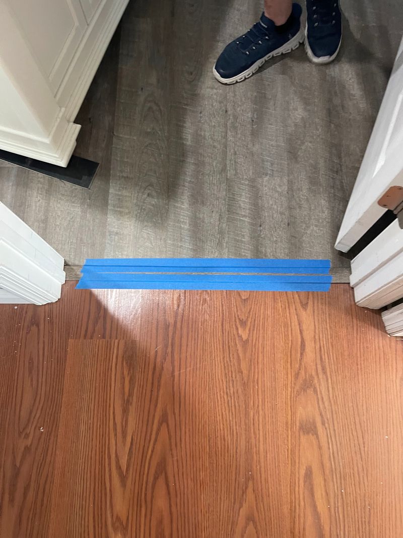 Doorway where gray vinyl plank meets a warm wood-tone floor