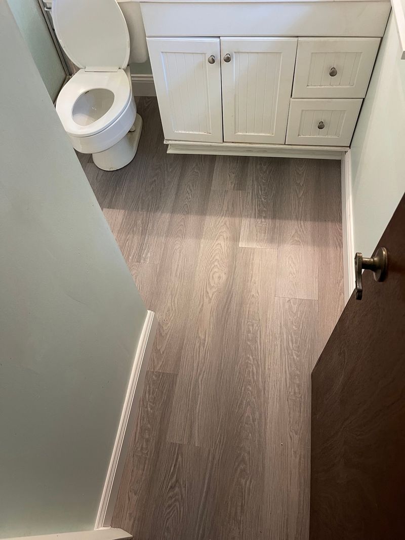 Bathroom with gray wood-look vinyl plank flooring and white vanity