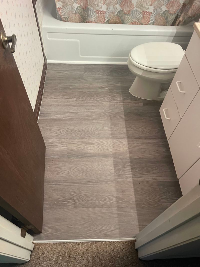 Second bathroom with gray wood-look vinyl planks, tub and toilet