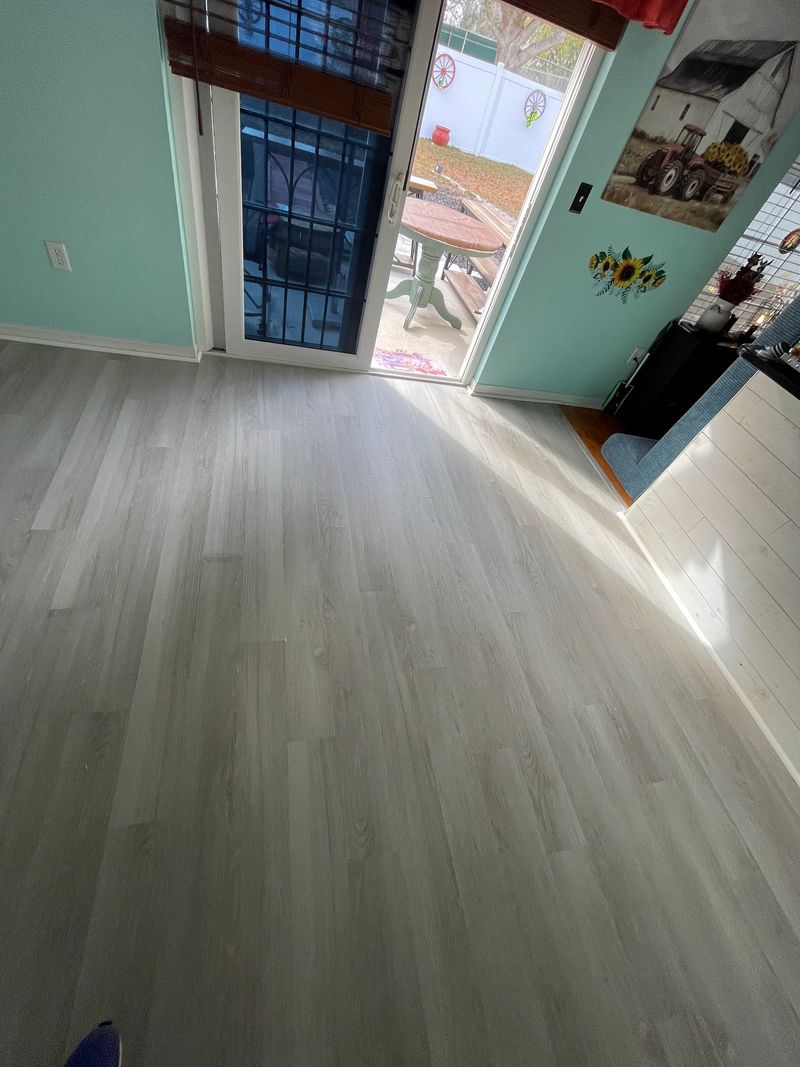 Living area with old light gray plank flooring before replacement
