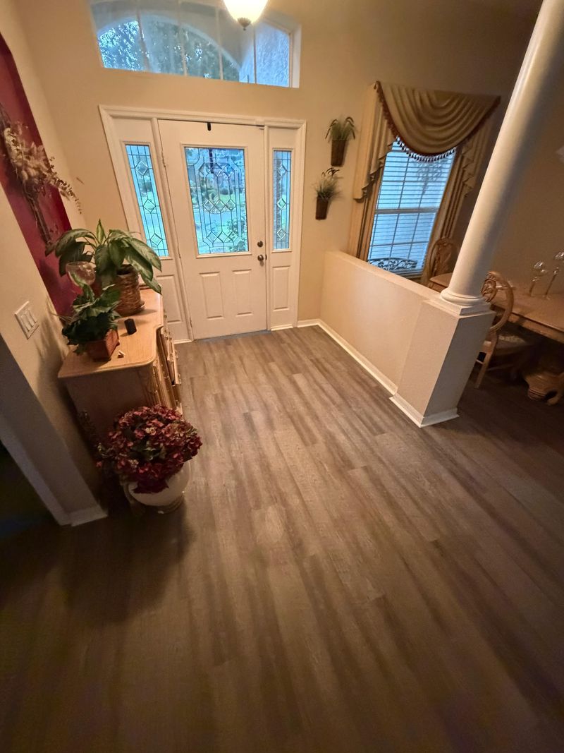 Entry foyer with new gray wood-look vinyl plank flooring and white baseboards
