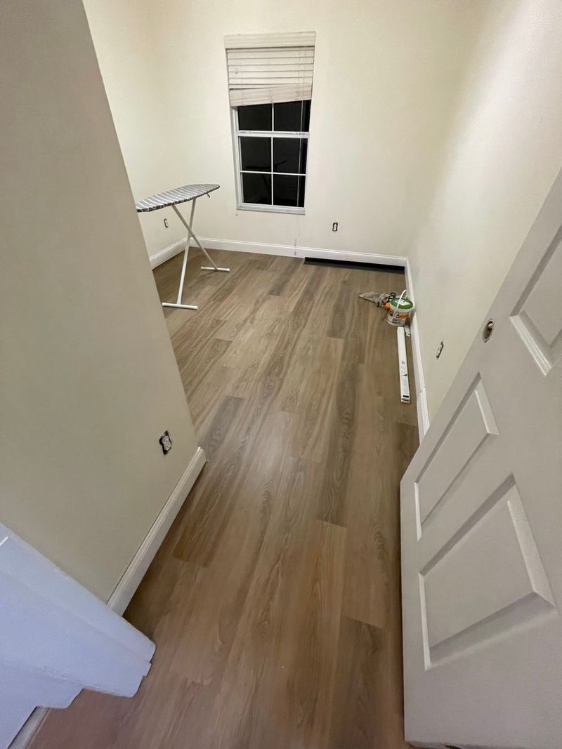 Bedroom with new gray-brown vinyl plank flooring and white baseboards