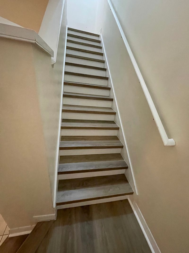 Full staircase with gray-brown vinyl plank treads and white risers