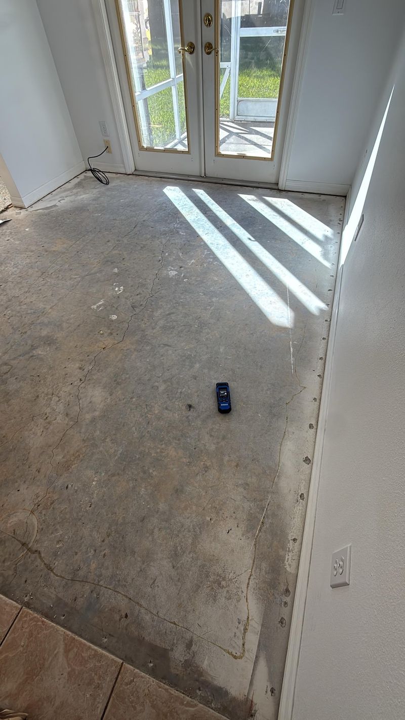Carpet removed, leaving the bare concrete slab by the French doors