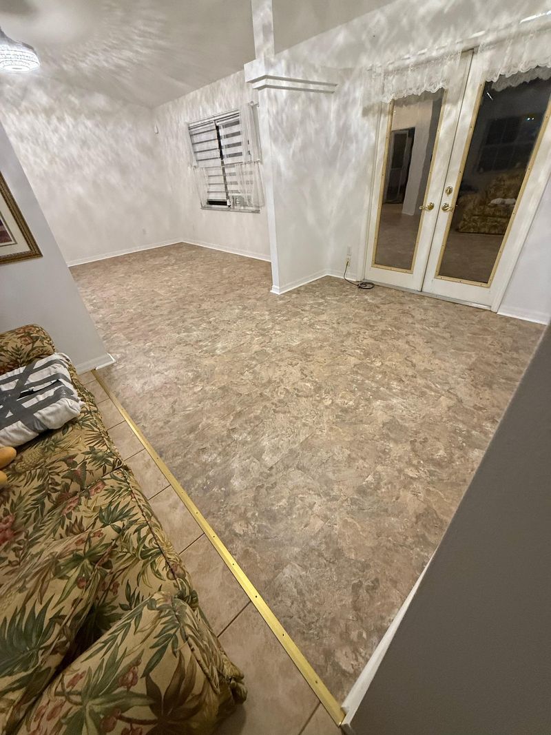 Living area with new beige mottled vinyl floor and brass transition to tile