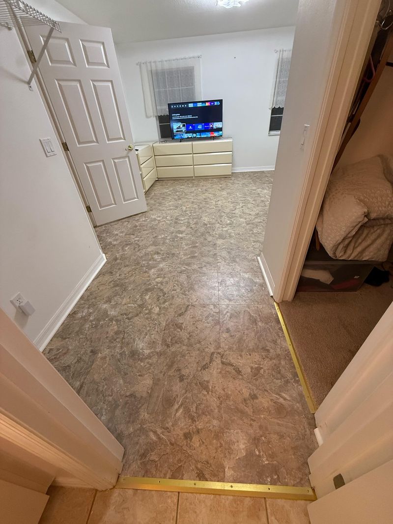 Bedroom doorway with new beige vinyl floor and brass threshold strip