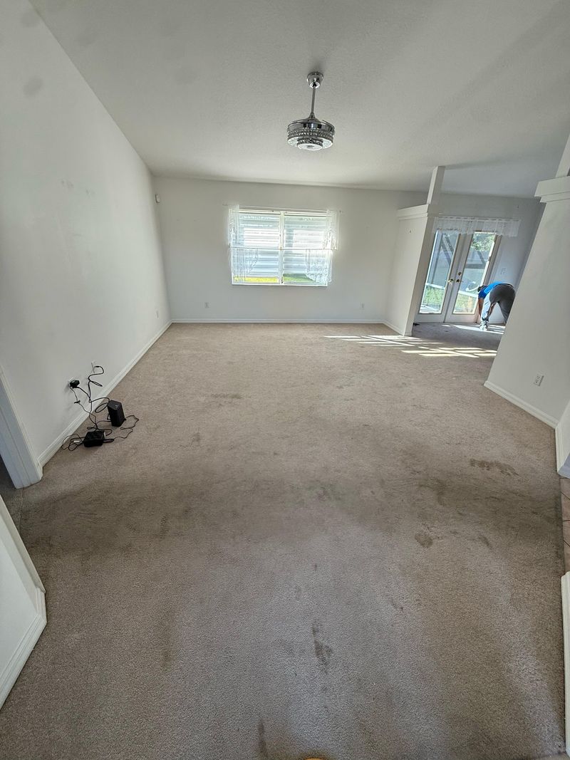 Long living area with stained beige carpet before removal