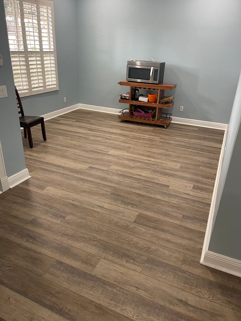 Breakfast area with new gray-brown wood-look vinyl plank and white baseboards