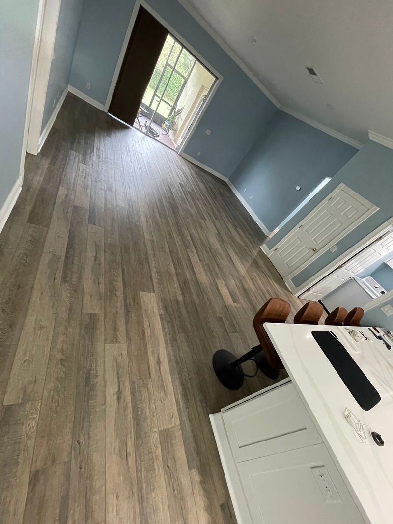 Open living area with long gray-brown vinyl plank runs toward patio doors