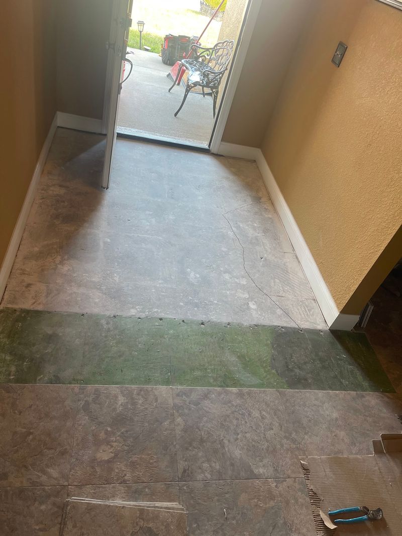 Entry hallway with old flooring removed and stone-look vinyl being laid