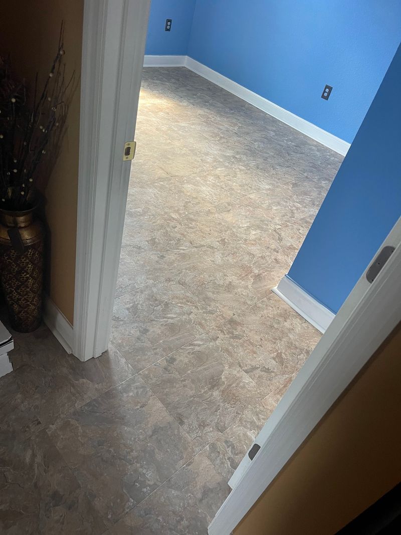 Blue bedroom finished with gray-brown stone-look vinyl flooring and white baseboards