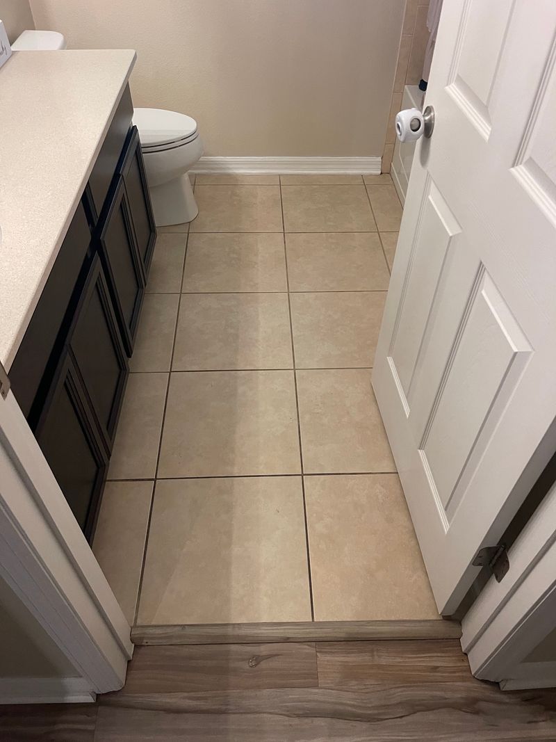 Bathroom with old beige ceramic tile floor and dark vanity