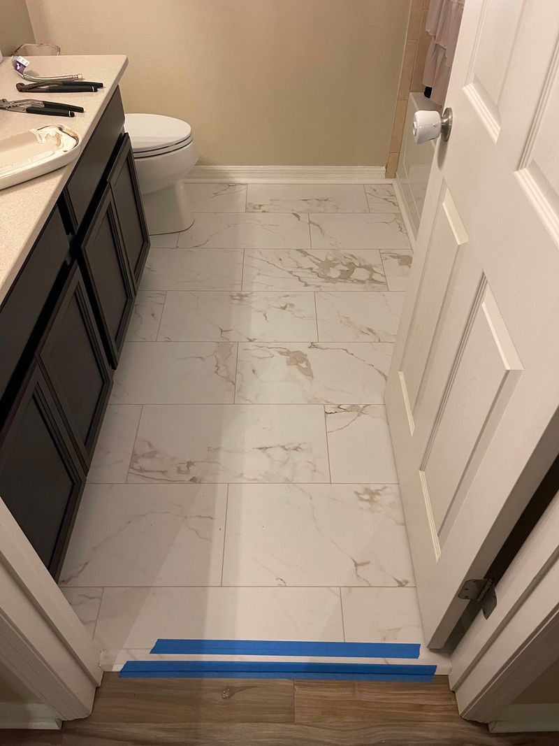Same bathroom with new white stone-look vinyl floor and dark vanity