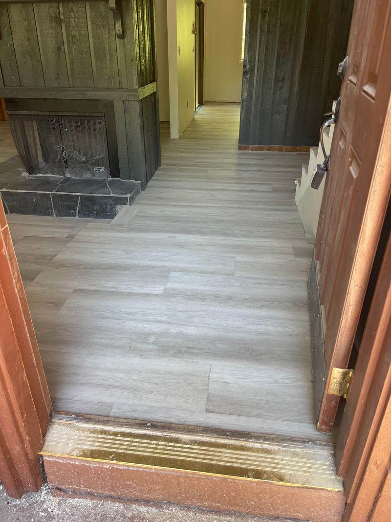 Entry with light gray wood-look vinyl plank running past a fireplace
