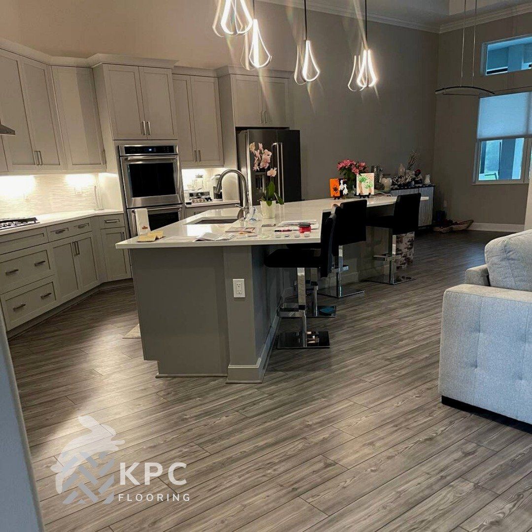 Gray wood-look plank flooring around a kitchen island with pendant lights